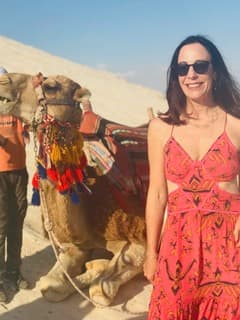 Sandra Hodes standing beside a camel in the desert