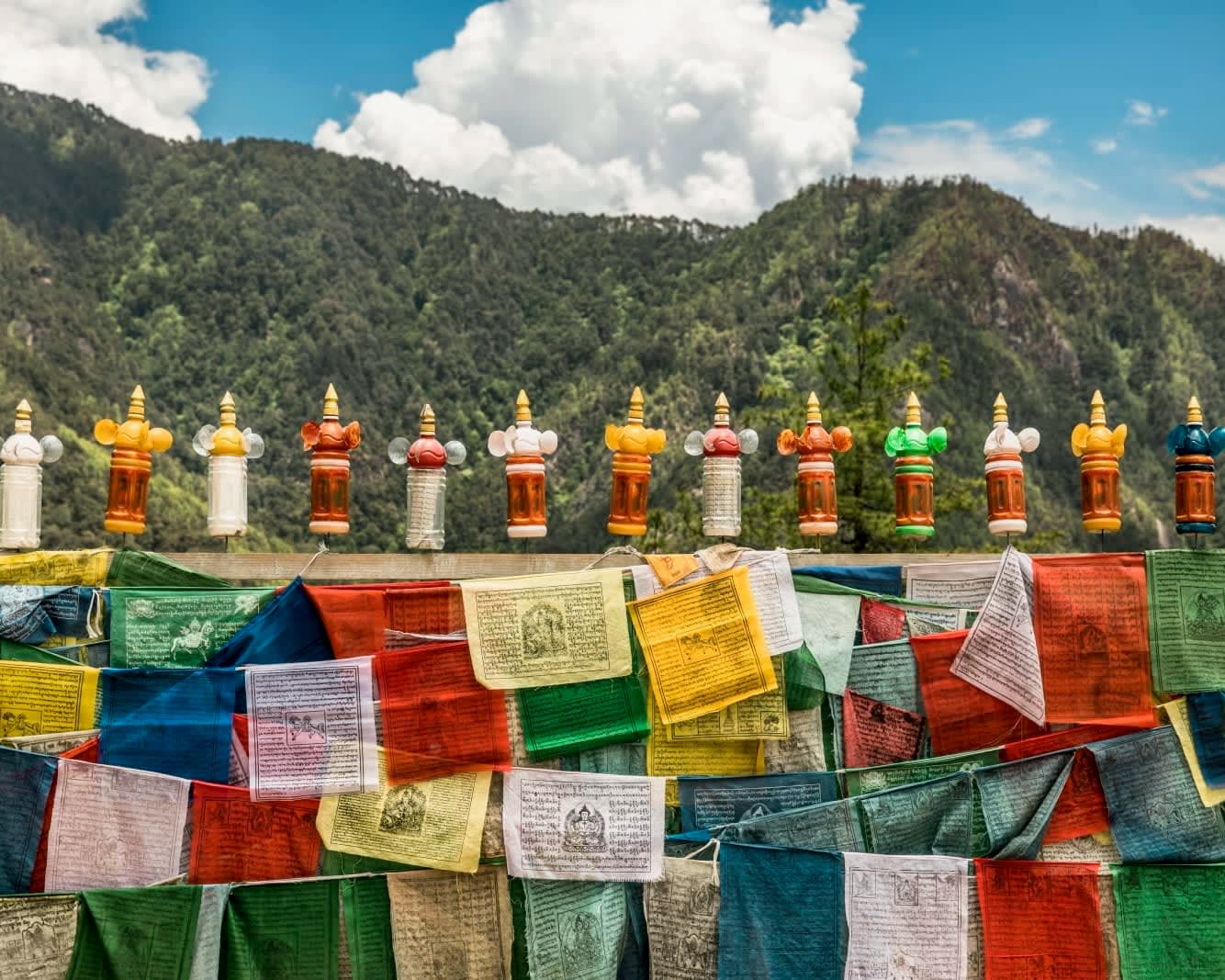colorful prayer flags under a green mountain