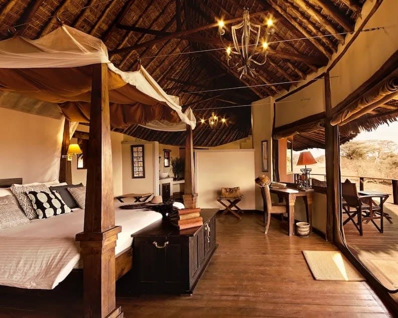 a vaulted luxury safari tent with four poster bed, wood floors, and chandelier