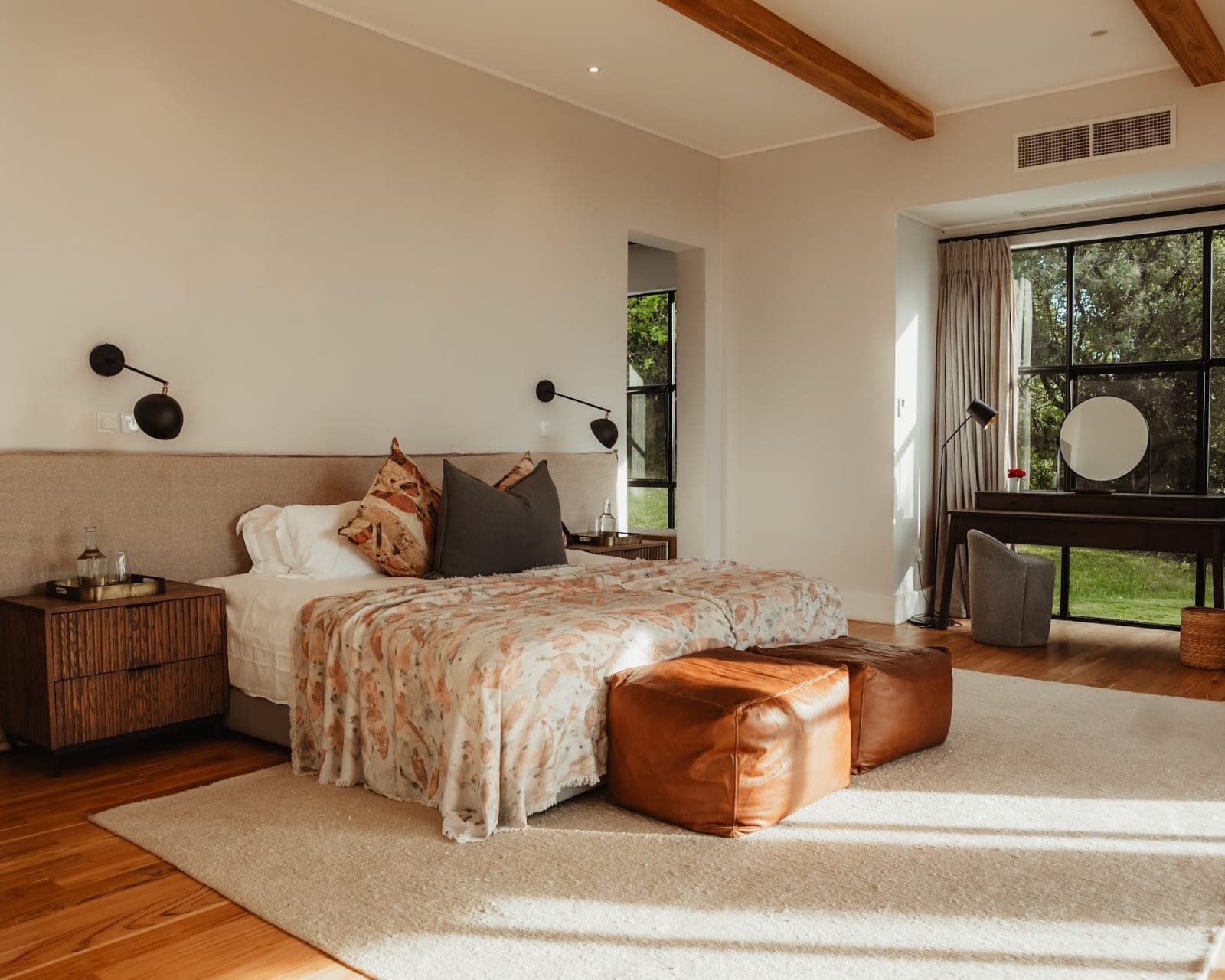 Warm bedroom with patterned cover on the bed, brown furniture, white walls and rug