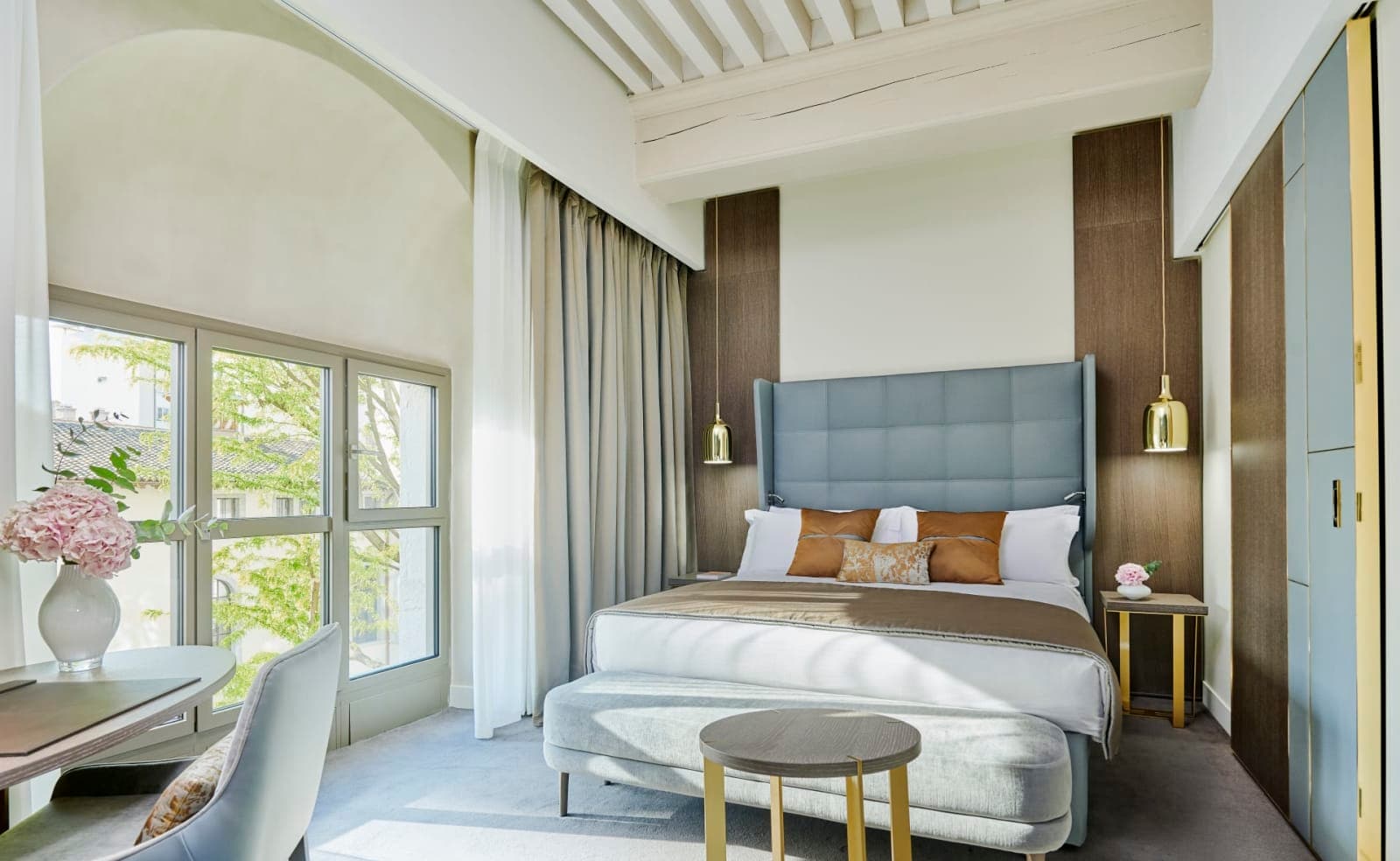 A contemporary room with dark wood accents, like blue bed headboard, white walls and white wood ceiling