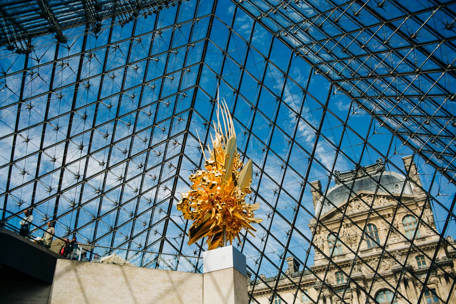looking at the sky through a glass pyramid with a golden sculpture